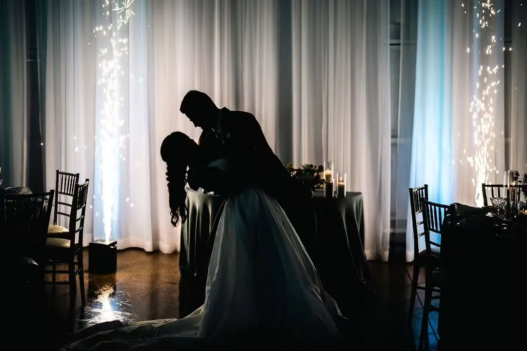 Silhouette of bride and groom sharing a romantic dip during their first dance at Ruby Oaks Events ballroom in Central Florida, framed by dramatic cold sparkler fountains and white drape backdrop