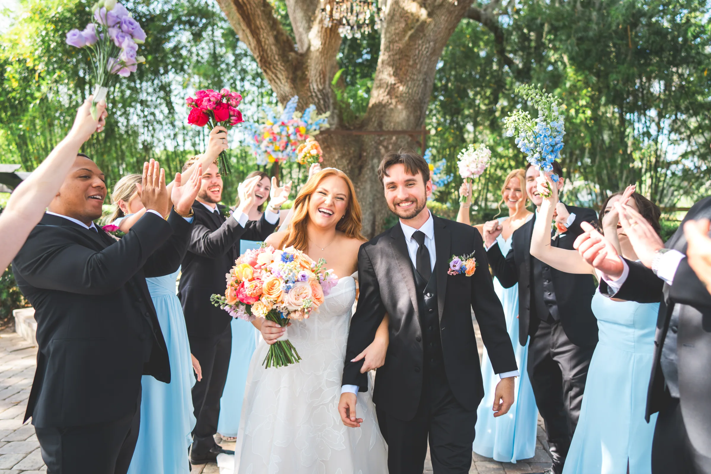 Couple walking down the aisle after just getting married. Bridal party surrounded them with big smiles. Rustic wedding style.