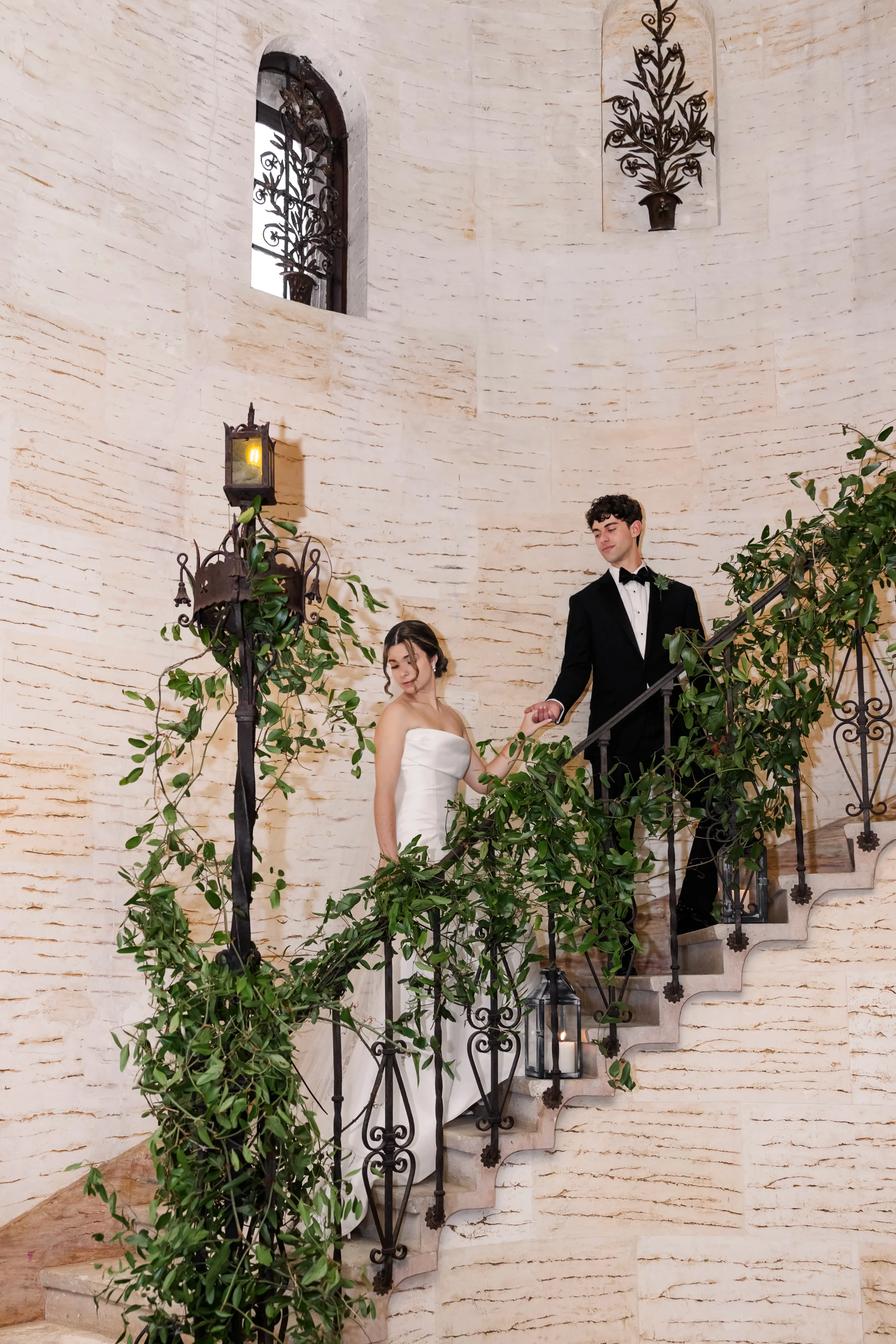 bride and groom on a staircase wrapped with greenery at the Howey Mansion venue for their timeless charm wedding. 