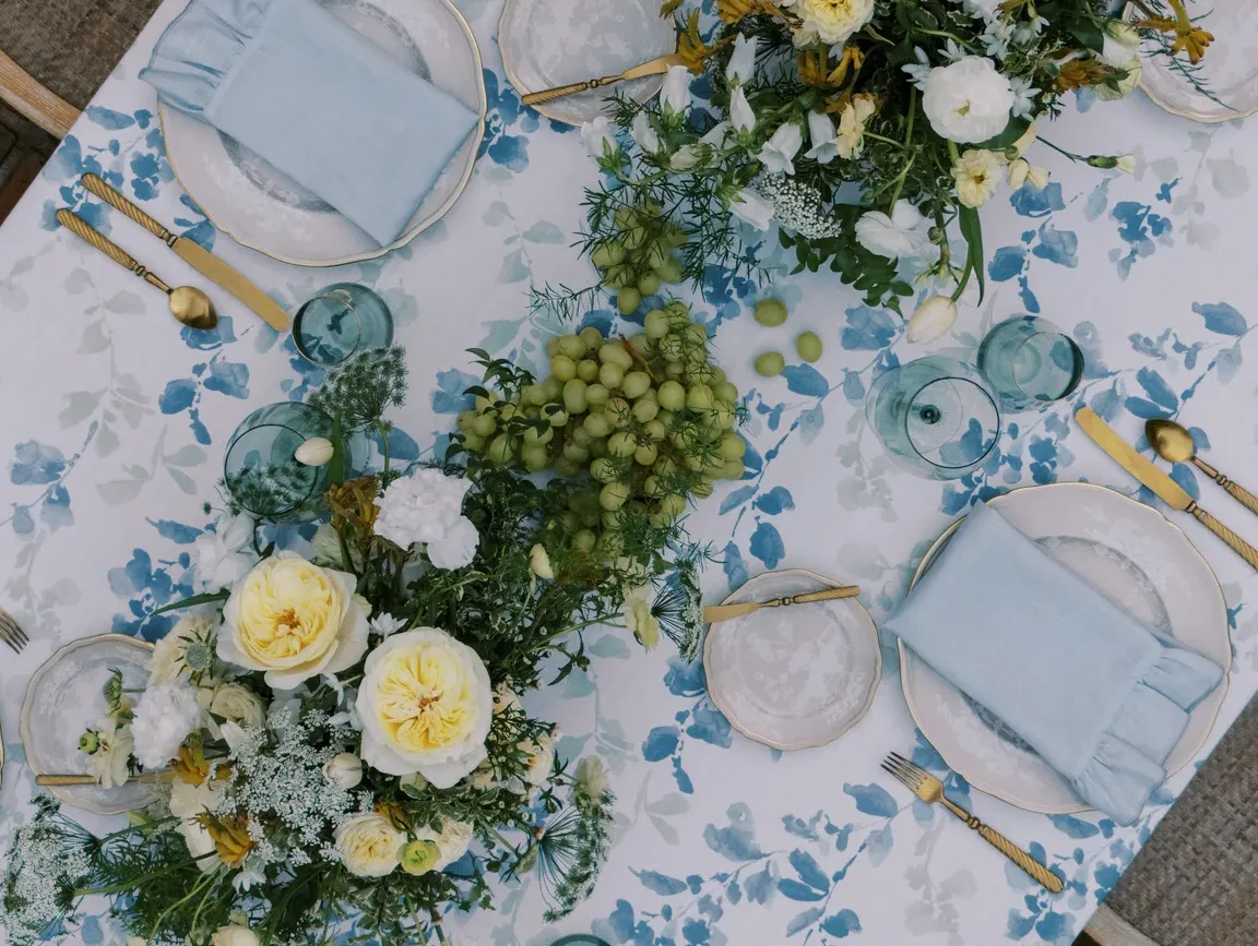 an image of a tablescape at a wedding featuring lush creams and blues with floral printed linens and ruffled light blue napkins, meant to represent 2026 wedding themes in Central Florida.