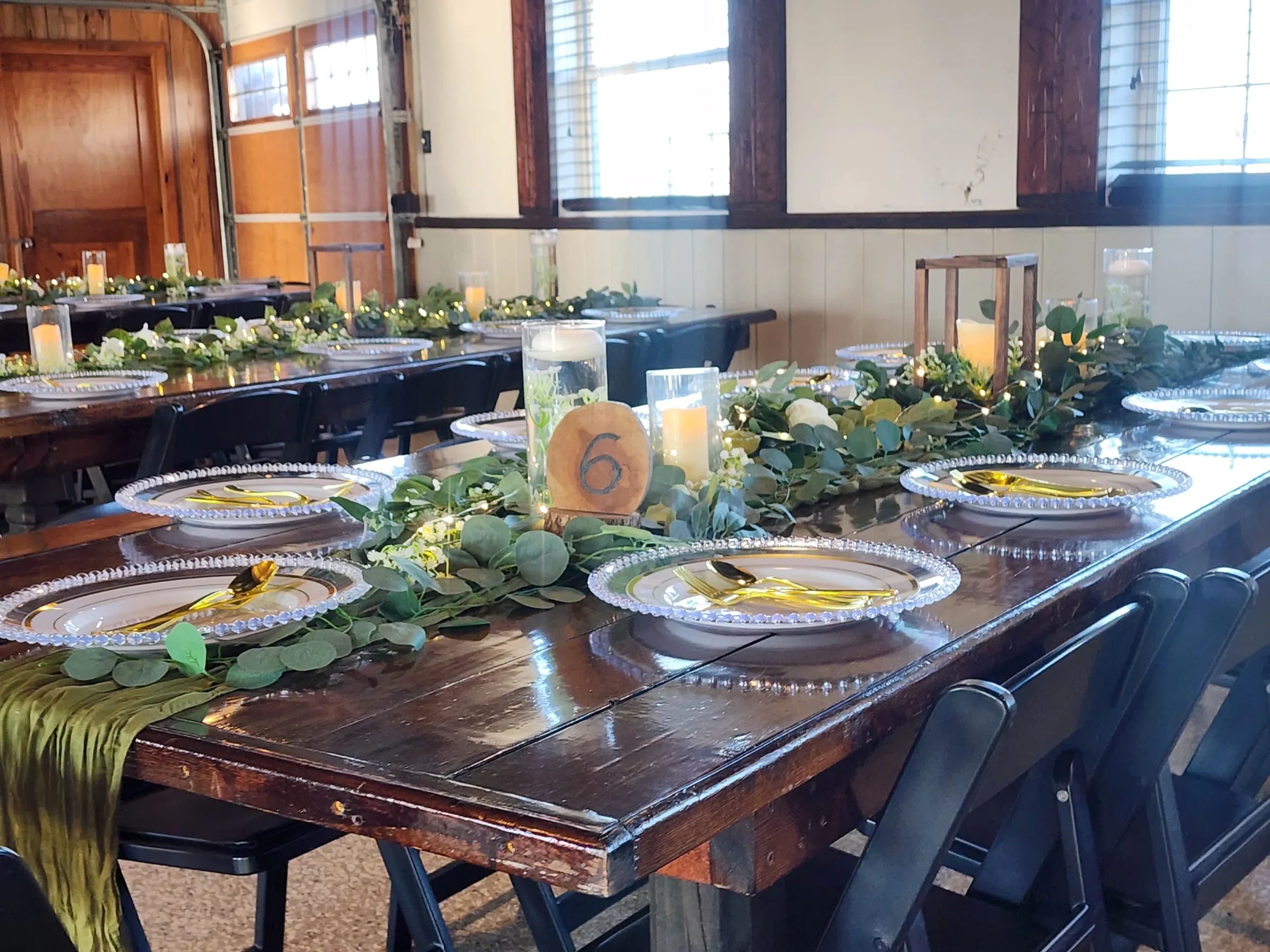Wedding reception table at The Ranch at St. Cloud with greenery garland, candles, table number, and mixed décor elements including items from venue décor closet.