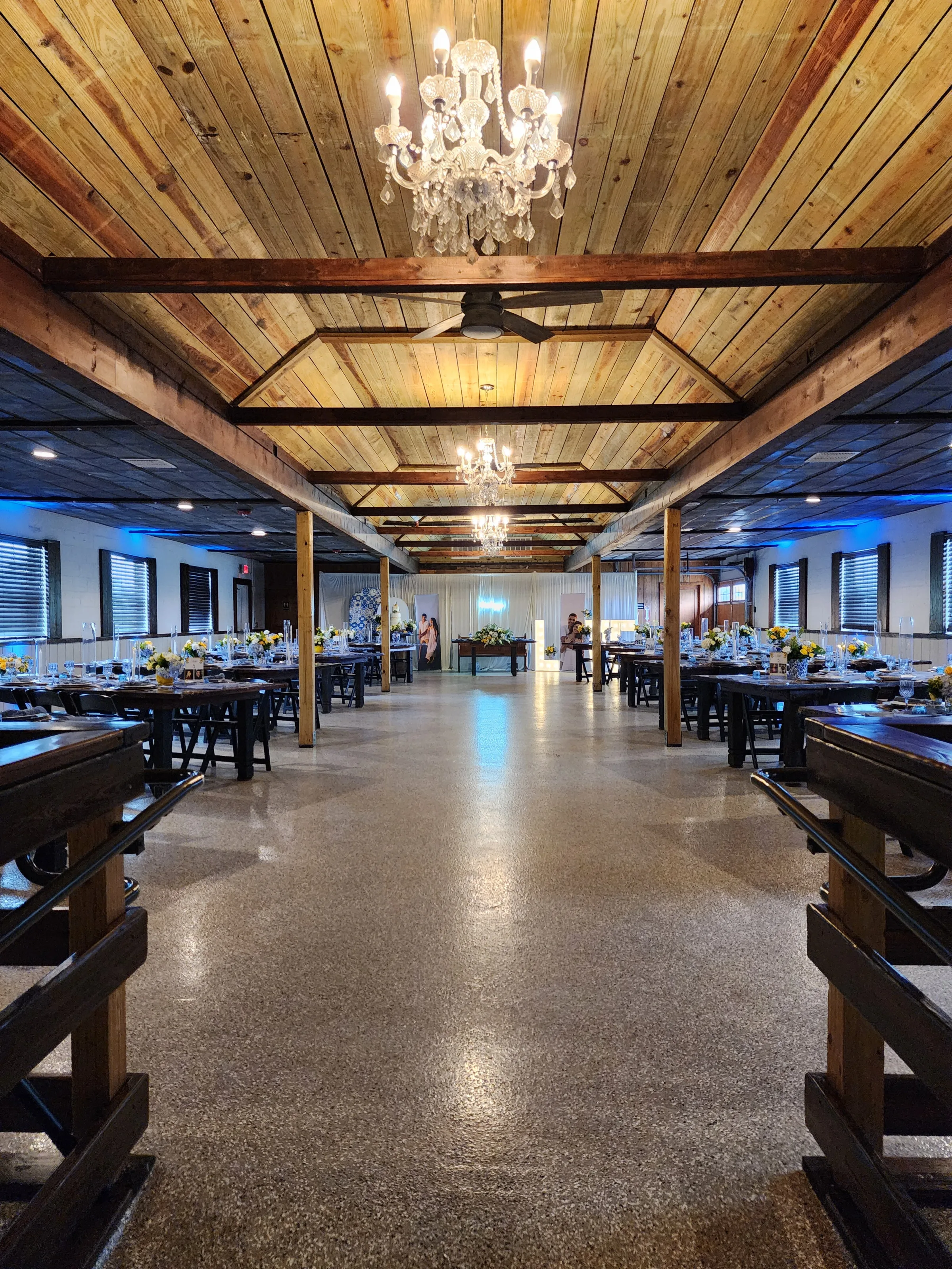 Decorated reception barn at The Ranch at St. Cloud with long farm tables, chandeliers, and wedding table settings.