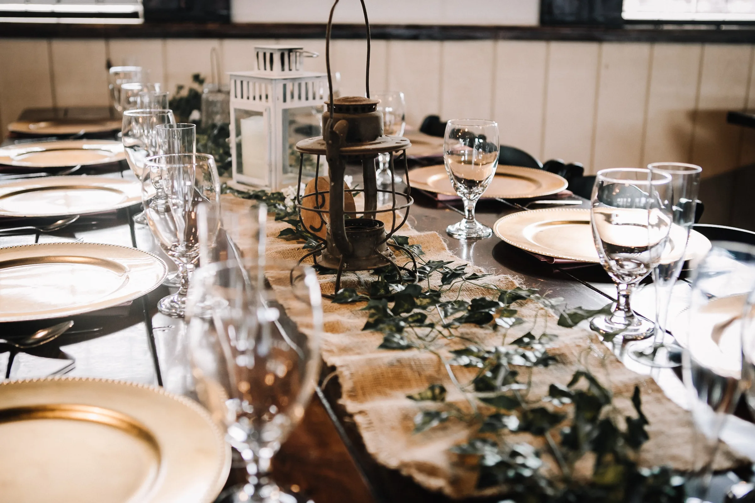 Rustic wedding table at The Ranch at St. Cloud with lantern centerpiece, greenery runner, and décor from venue décor closet.