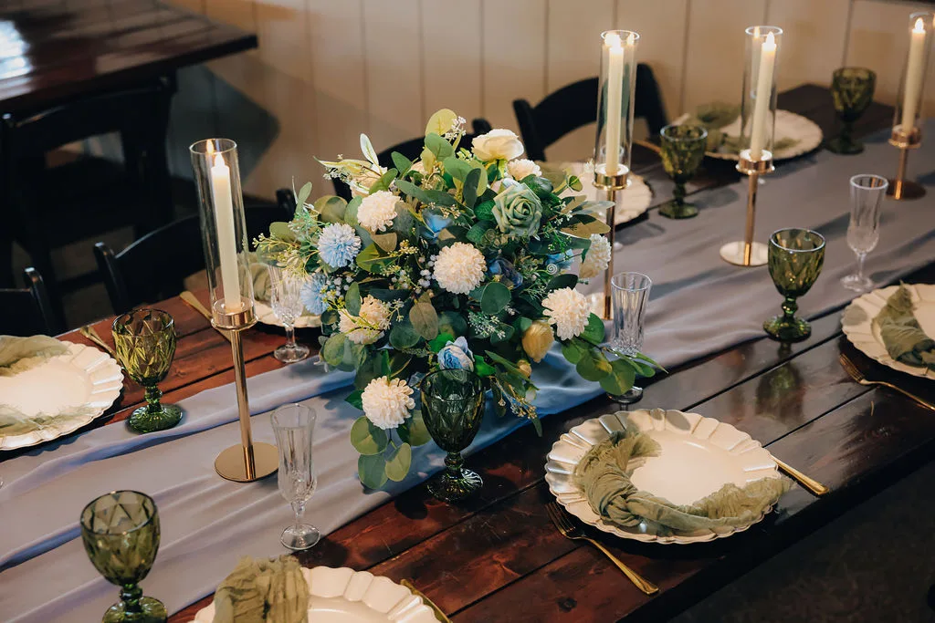Close-up of decorated farmhouse table at The Ranch at St. Cloud with floral centerpiece, candles, and place settings.