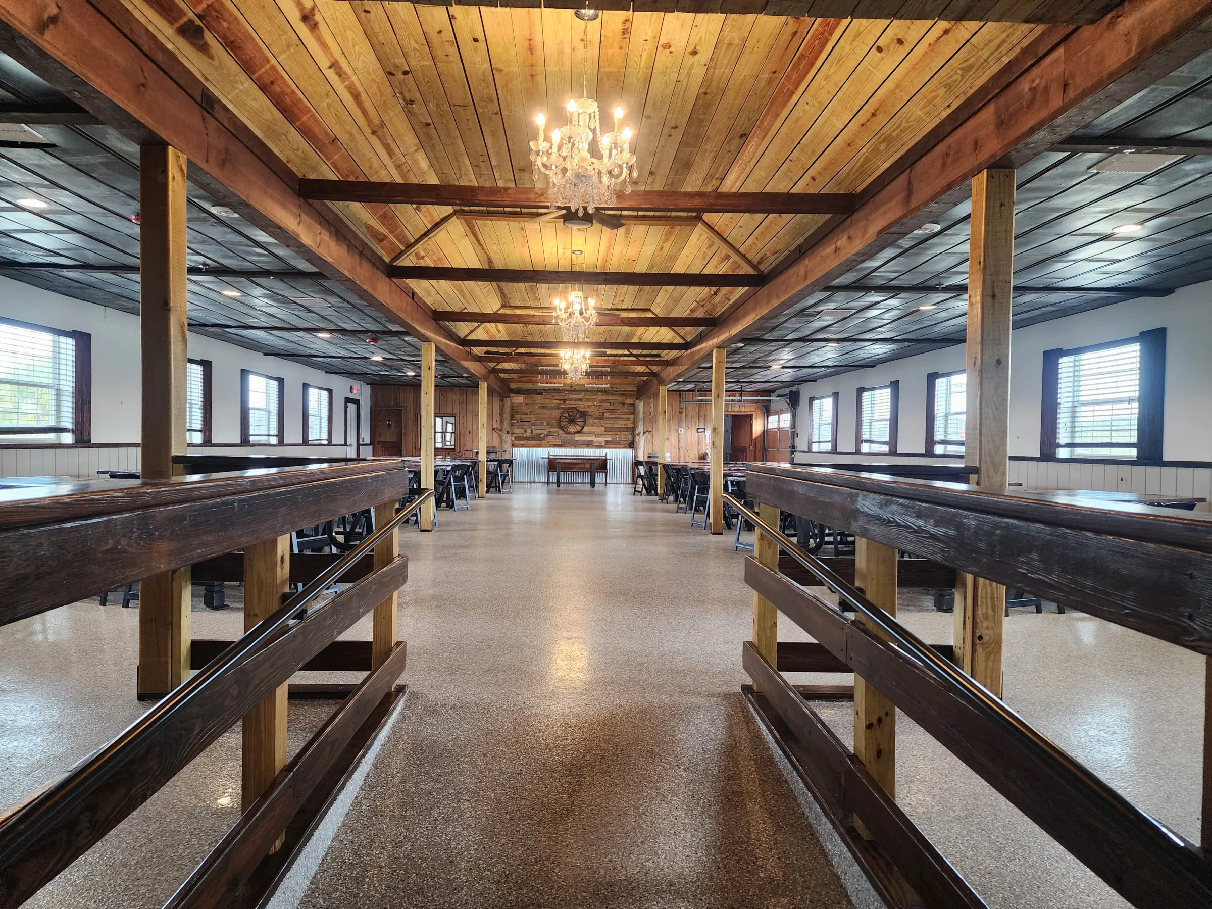 Entrance view of the main reception barn at The Ranch at St. Cloud with wood beams, chandeliers, and open dining space.
