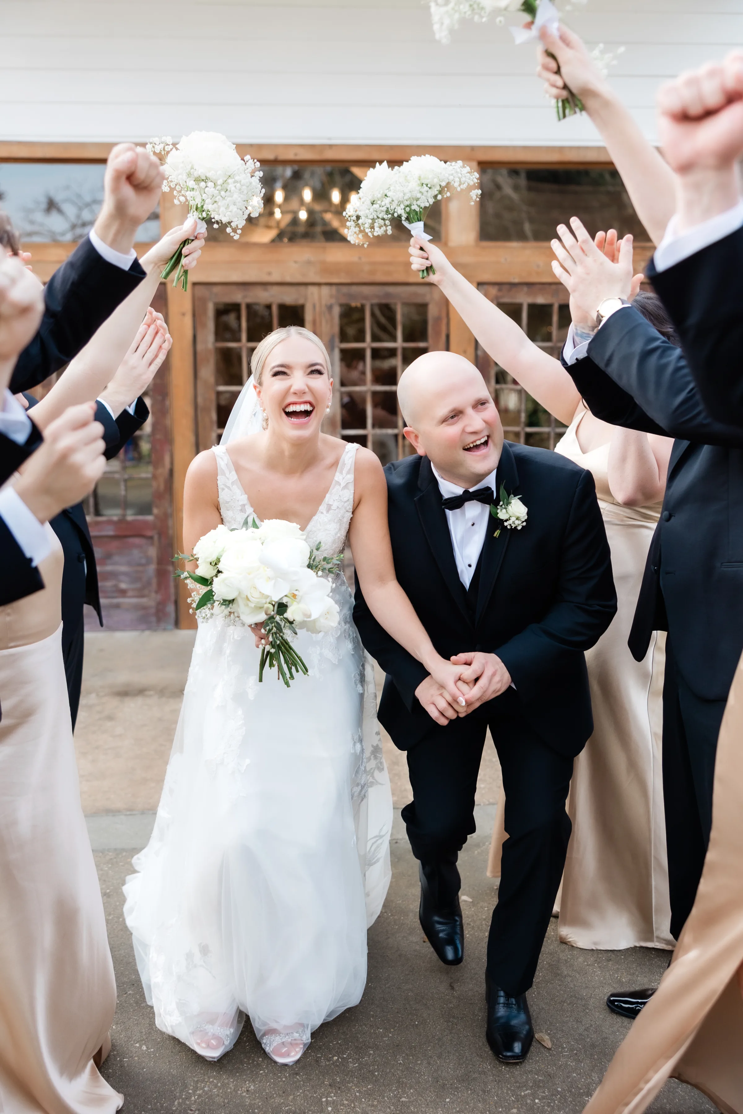 LZ Wedding 573 - Wedding Venue Shopping Tips Every Newly Engaged Couple Should Know bride and groom walking through cheering wedding party outside venue, showing guest experience for wedding venue shopping tips