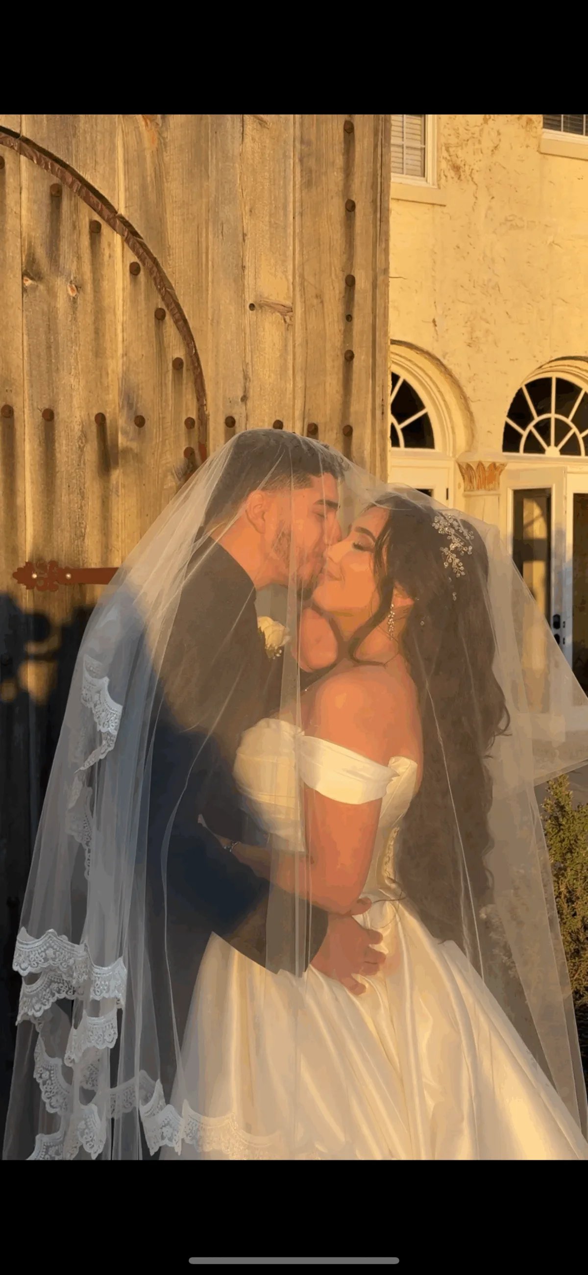 bride and groom sharing a romantic kiss under a lace-trimmed veil during golden hour at an Orlando Central Florida wedding venue, captured by a wedding content creator