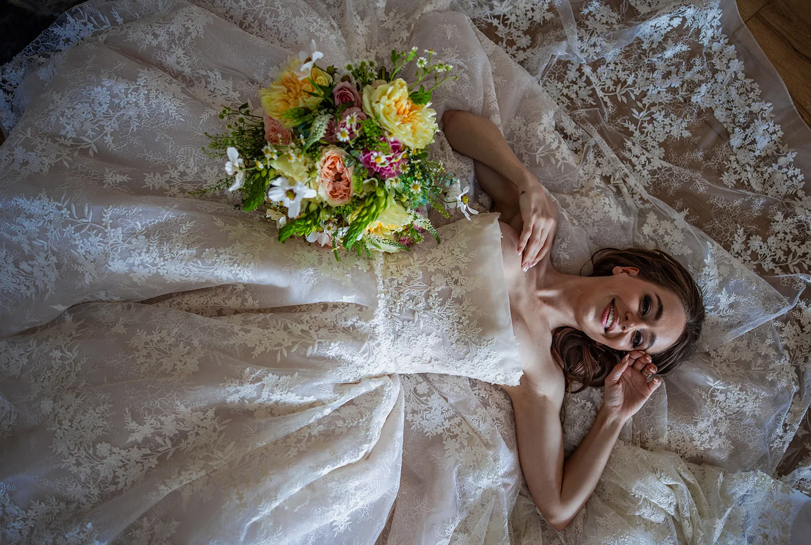 CY7A6954 - Organic Wedding Inspiration for Your Central Florida Wedding Bride laying on the floor with her floral bouquet smiling at the ceiling for this Organic wedding inspiration.