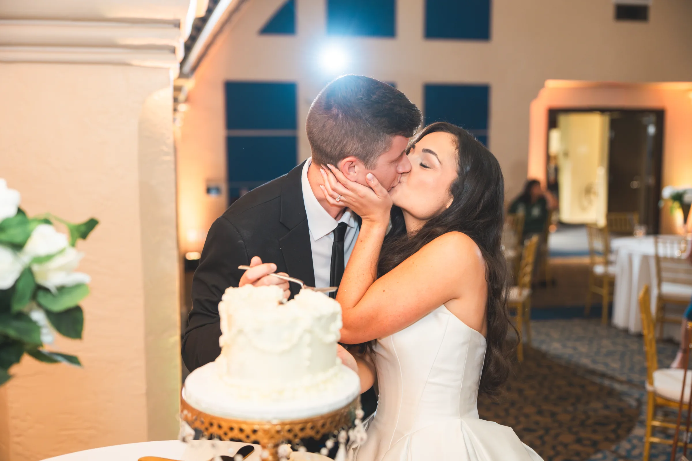 CodyKarinaWedding03 15 2026 1404 - European Inspired Wedding | Rollins College Bride and groom sharing a kiss after trying their wedding cake for the first time at their european inspired wedding reception at Rice Family Pavilion Rollins College