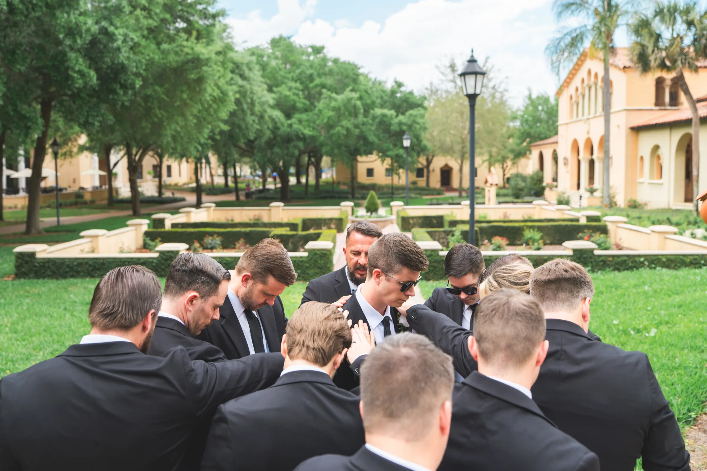 CodyKarinaWedding03 15 2026 335 - European Inspired Wedding | Rollins College Groomsmen gathered in prayer circle on Rollins College campus grounds before european inspired wedding ceremony