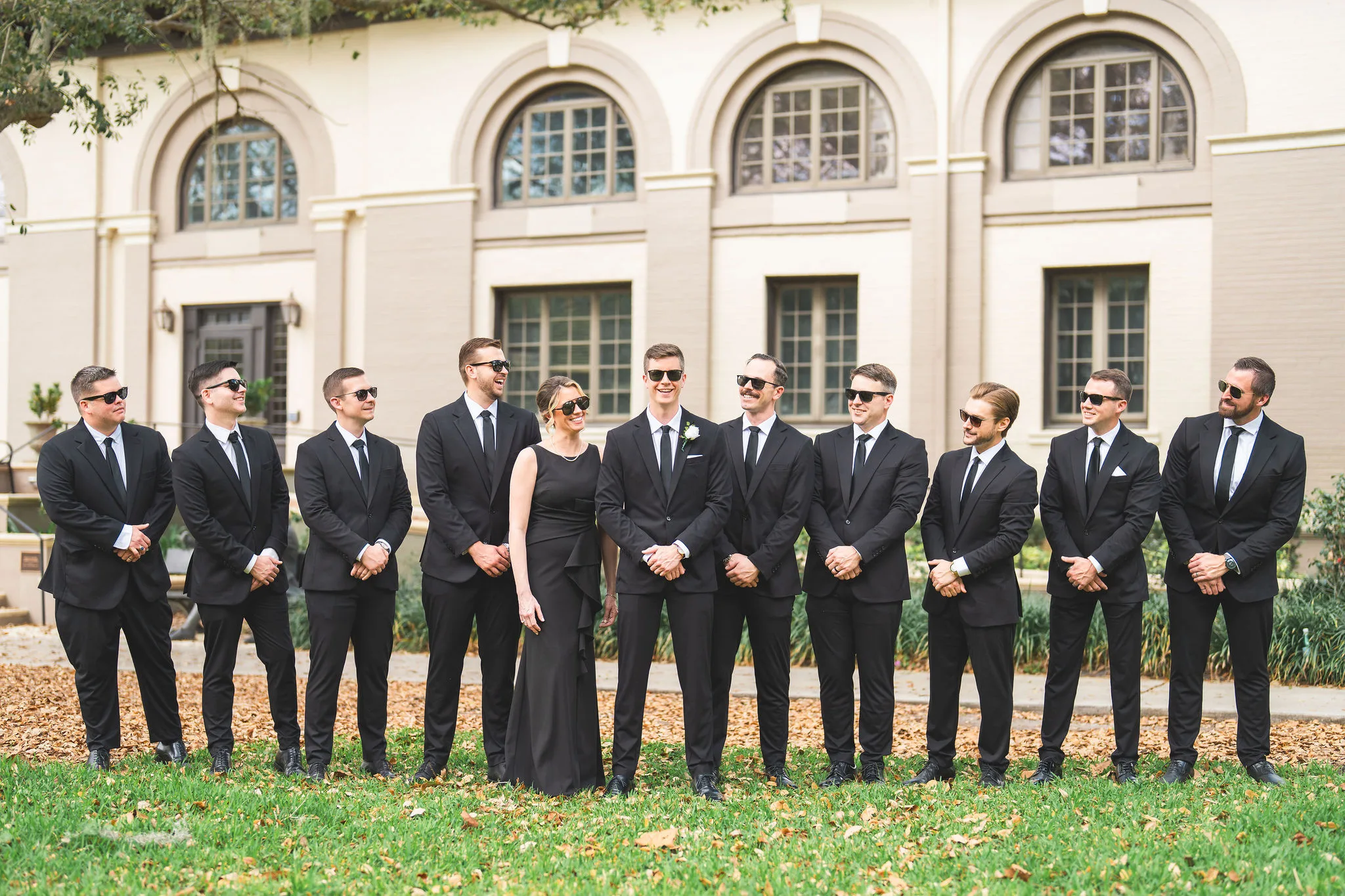 CodyKarinaWedding03.15.2026 267 - European Inspired Wedding | Rollins College Groomsmen in all black suits and sunglasses in front of Rollins College campus building