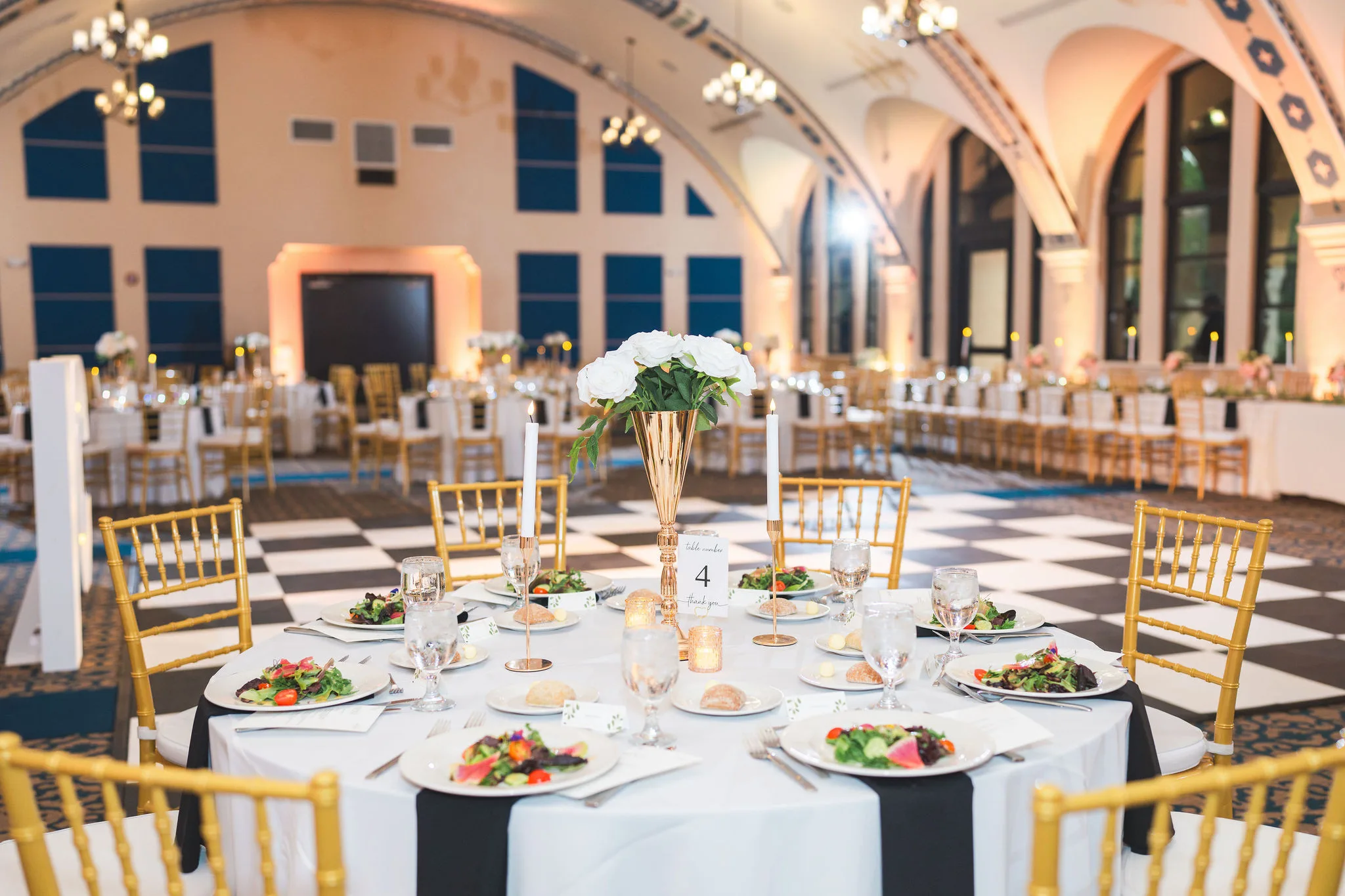 CodyKarinaWedding03.15.2026 846 - European Inspired Wedding | Rollins College Gold reception table setting with tall white floral centerpieces on checkered dance floor at European inspired wedding