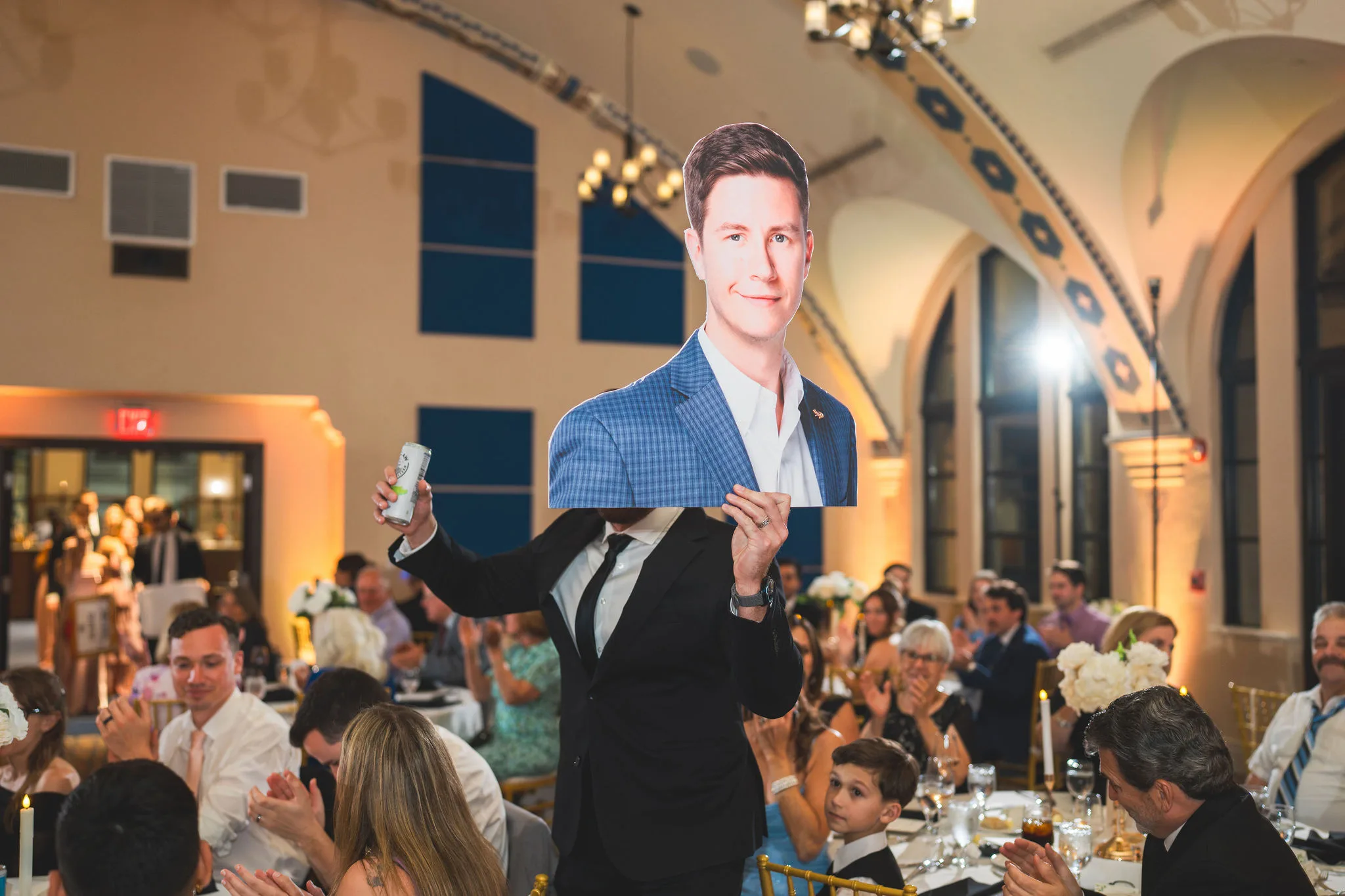 CodyKarinaWedding03.15.2026 934 - European Inspired Wedding | Rollins College Groomsmen waving the grooms head cut out around the reception with a white claw in their hand.