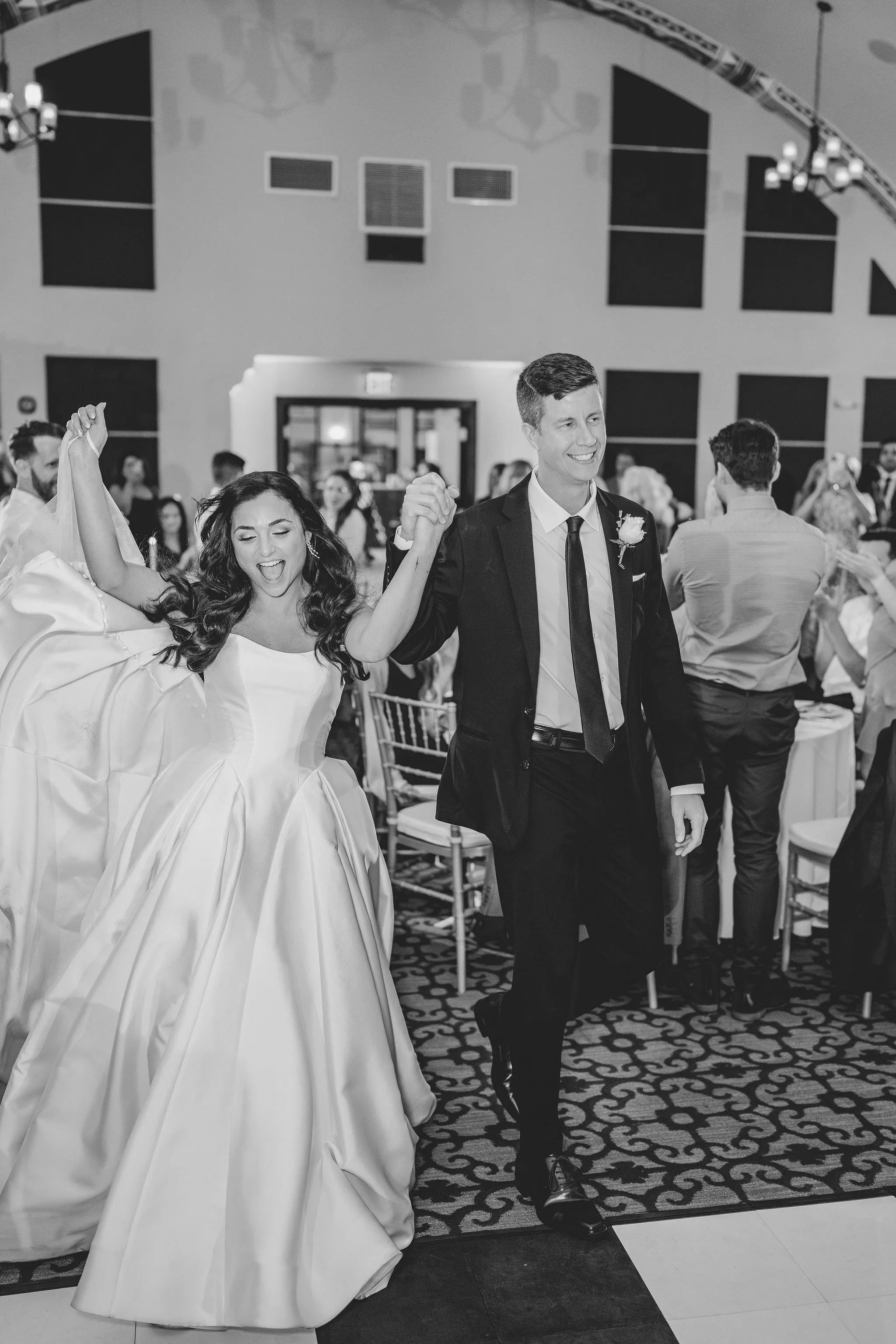 CodyKarinaWedding03.15.2026 983 - European Inspired Wedding | Rollins College Bride and groom walking out to their reception excited in black and white at their Rollins College european inspired wedding reception