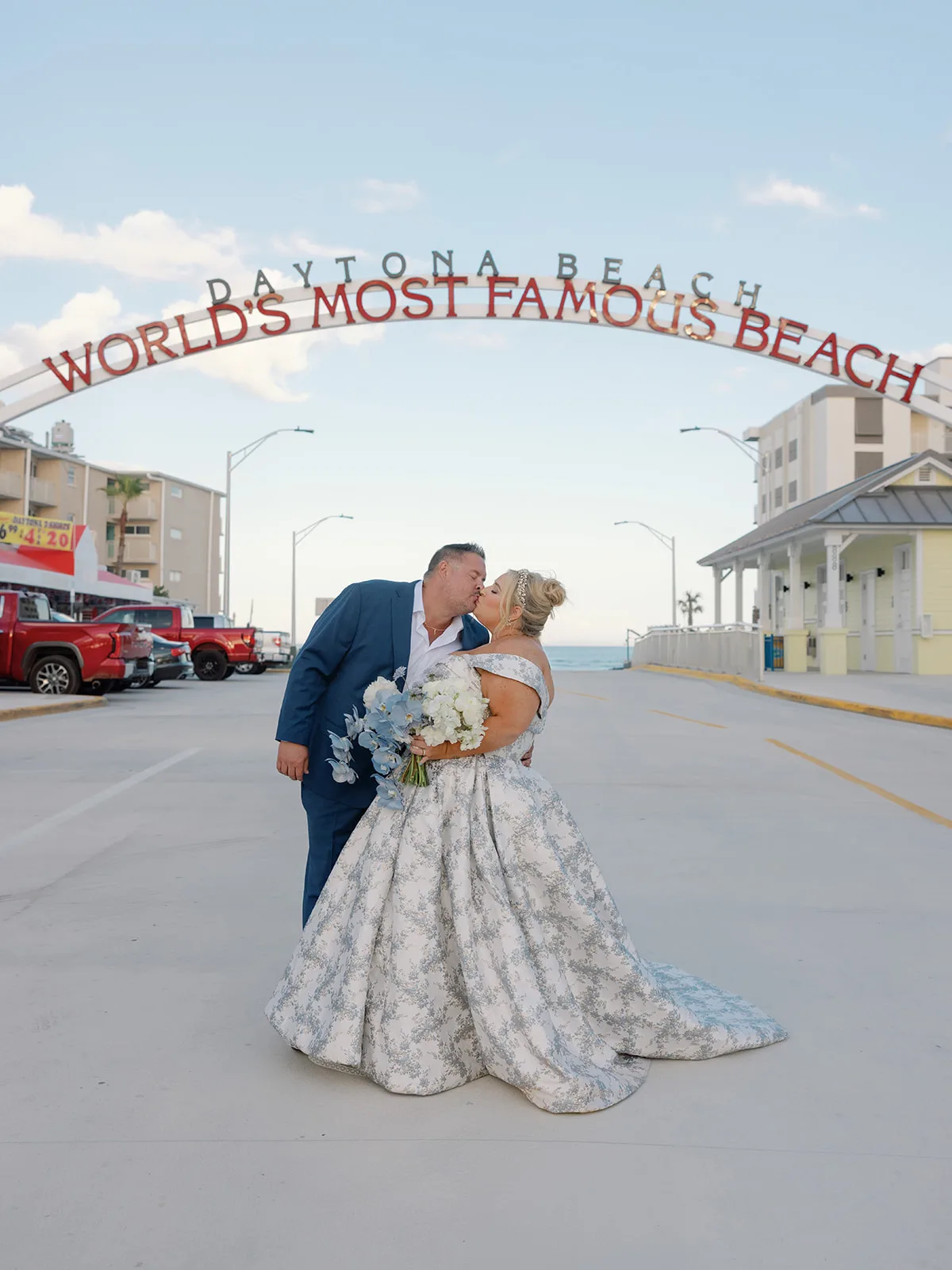 BB Post 149 - Romantic Blush and Blue Daytona Beach Wedding Bride and groom kissing in front of Daytona Beach sign