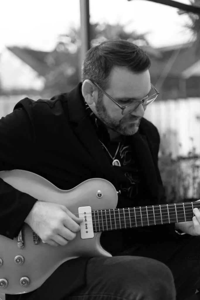 Musician playing electric guitar while creating custom wedding songs for couples