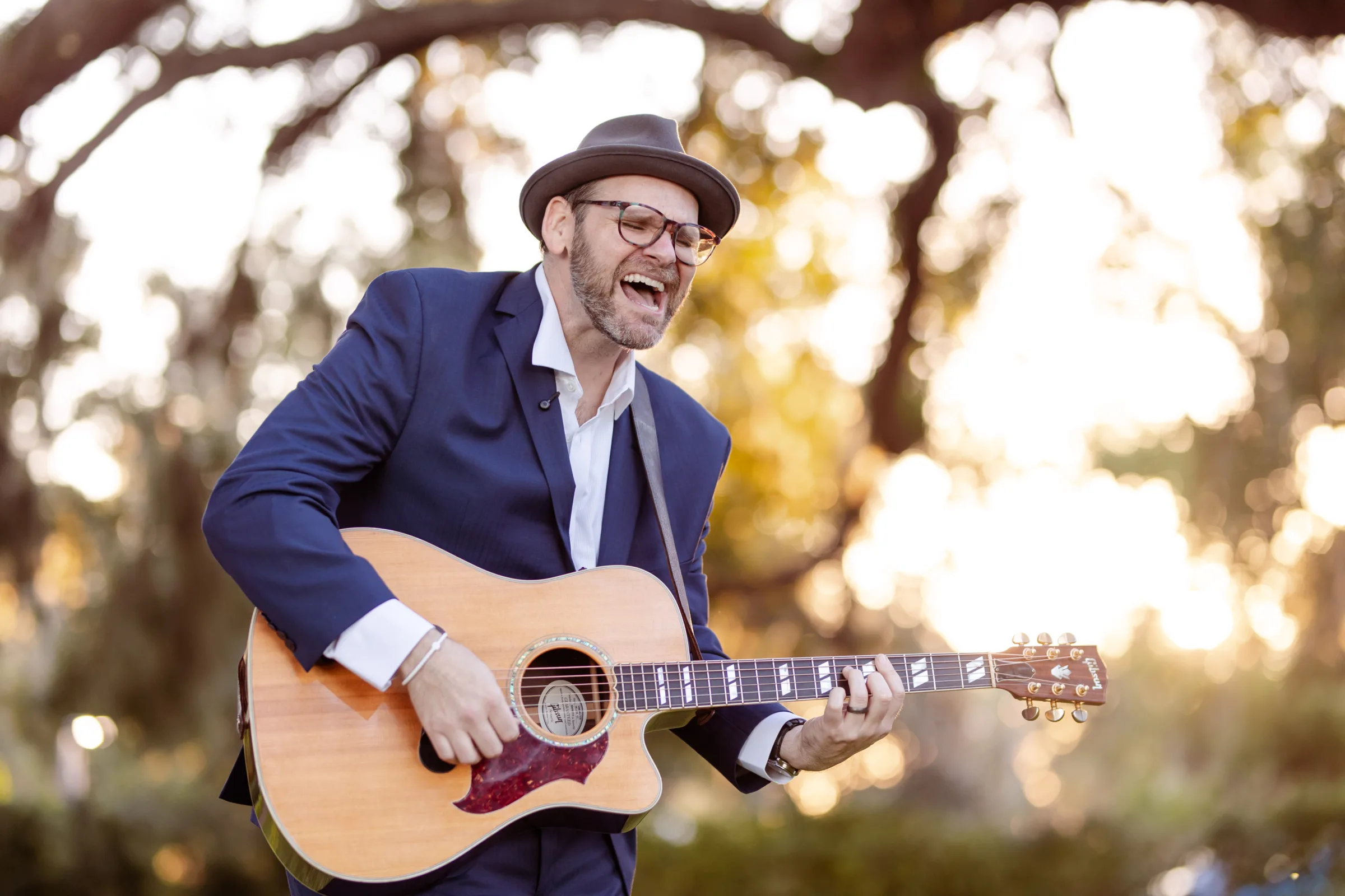 Wedding singer and guitarist performing outdoors with an acoustic guitar