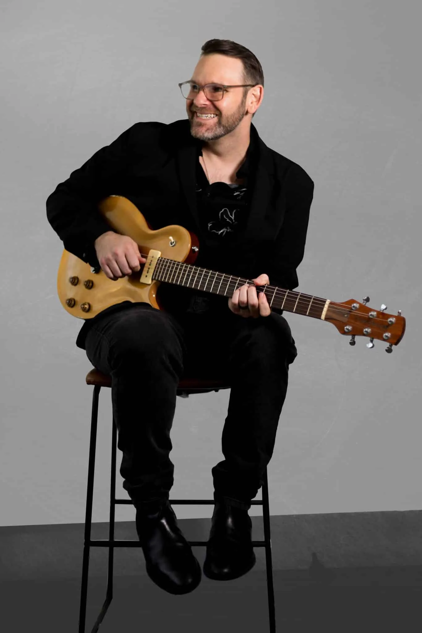 Custom wedding songwriter and musician posing with his guitar