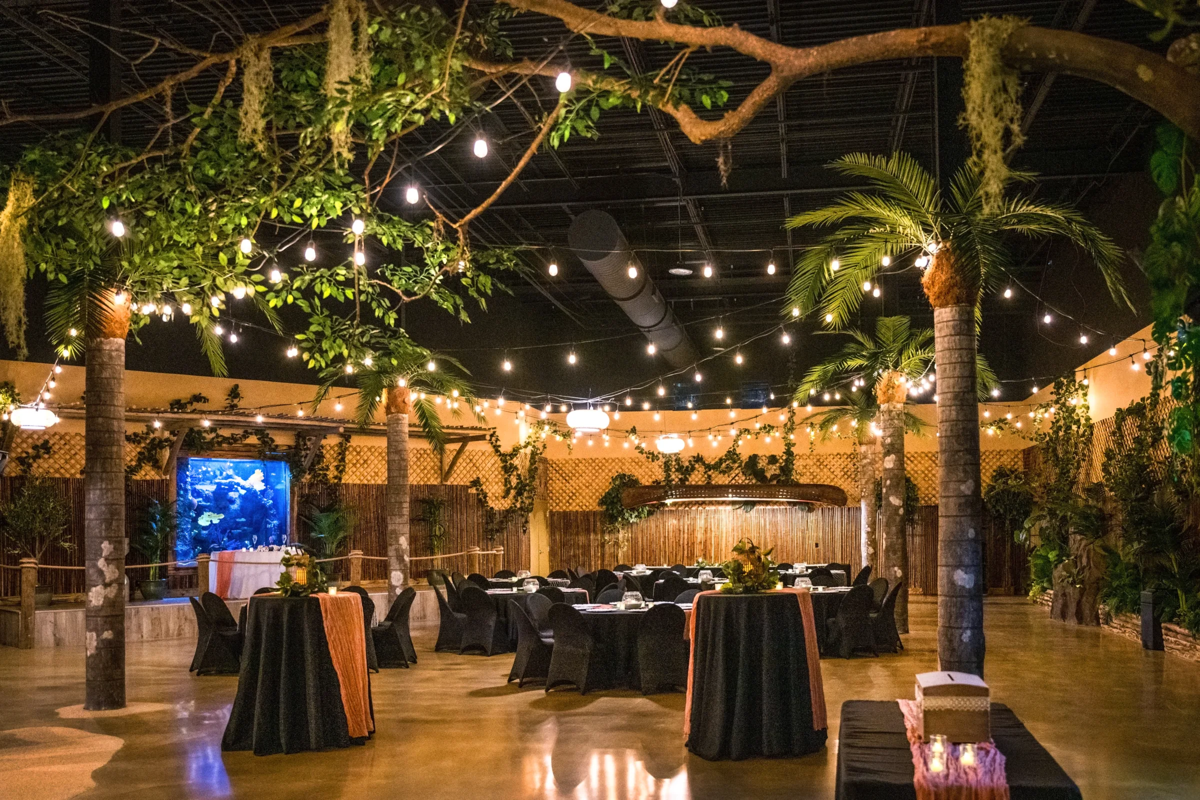 Tropical aquarium wedding reception with string lights