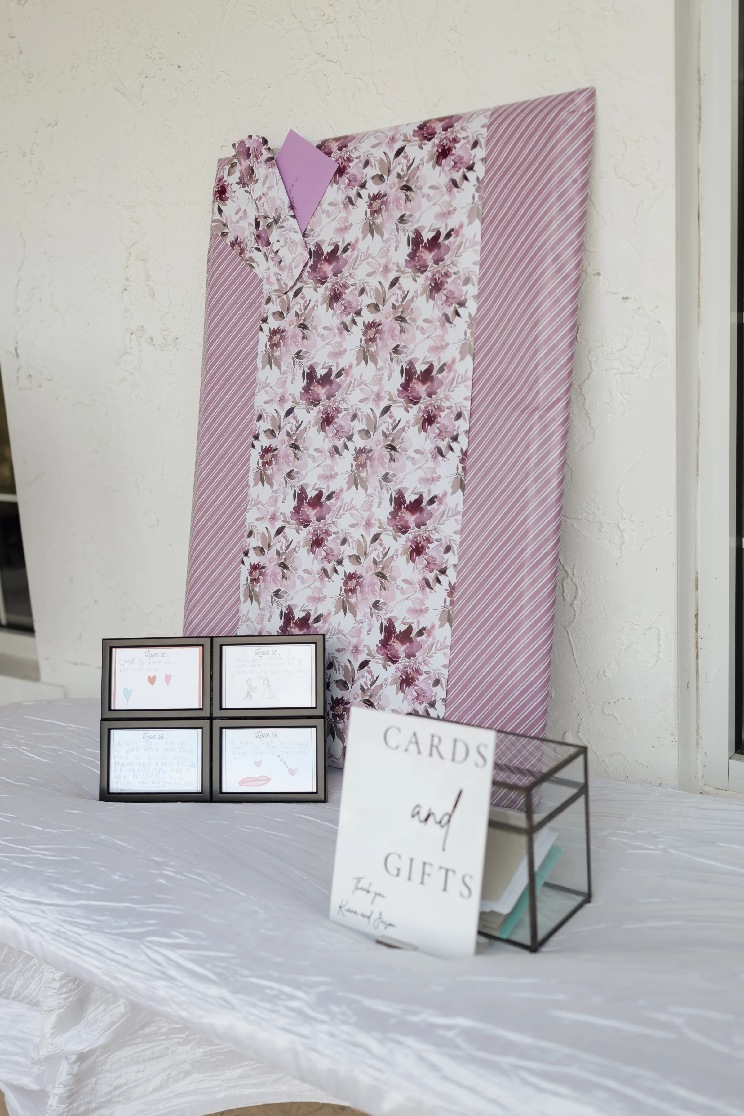 Elegant cards and gifts table with purple floral fabric backdrop, framed guest notes, and geometric card box at an Orlando Central Florida wedding reception
