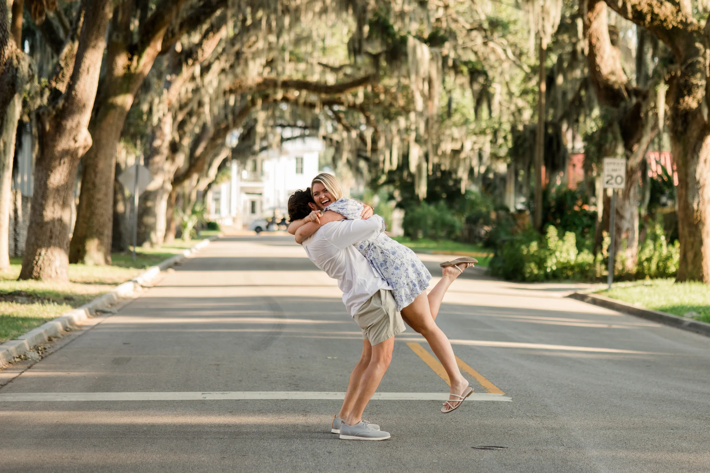 central florida proposal couple embrace tree lined street - Just Engaged? Now What? Joyful couple sharing an embrace in the middle of a tree-lined street draped in Spanish moss during a Central Florida proposal, photographed by Vanessa Oppedal Photography.