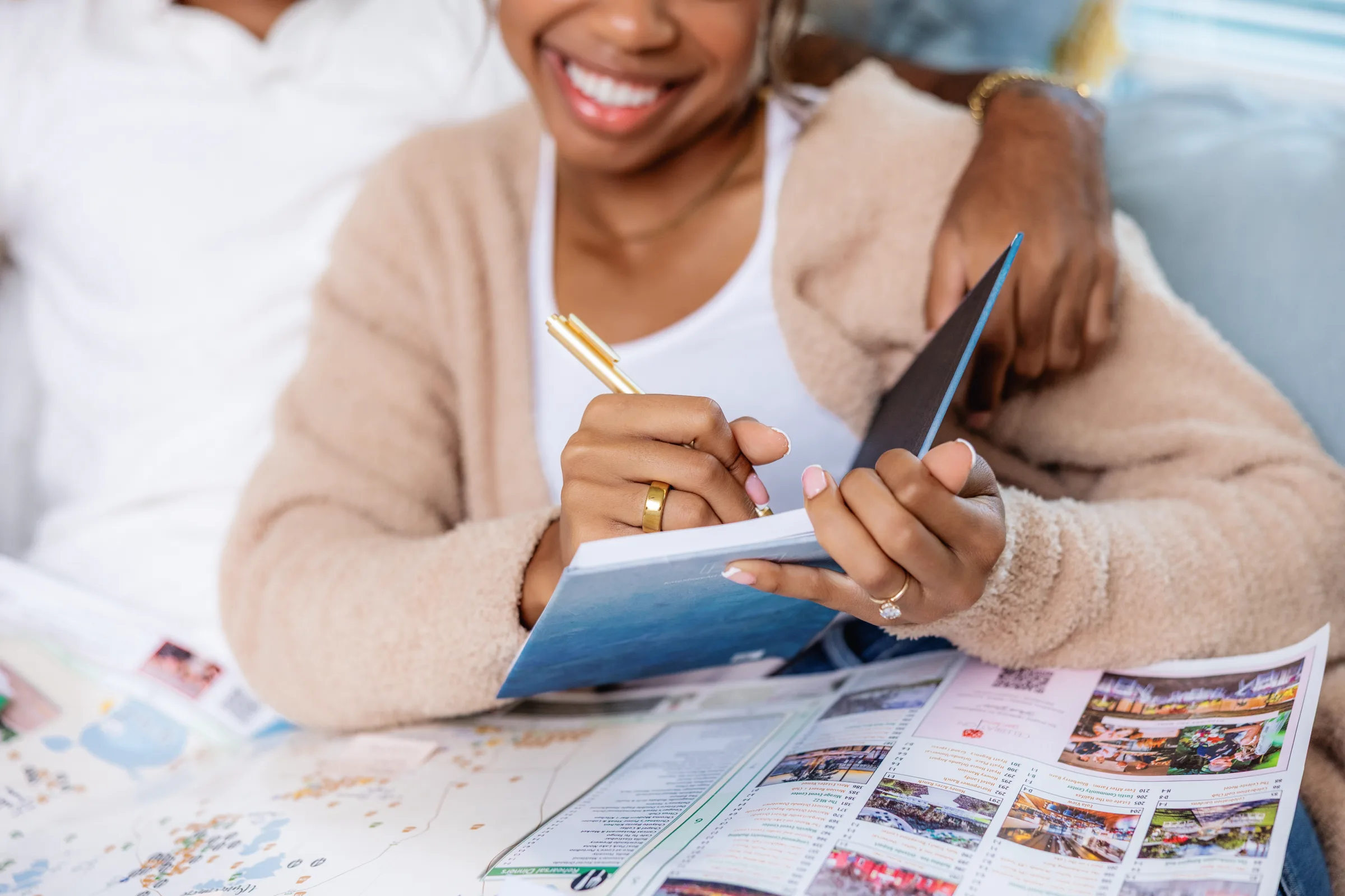 Smiling bride holding a pen and notebook reviews wedding venue brochures and maps while planning her Central Florida wedding