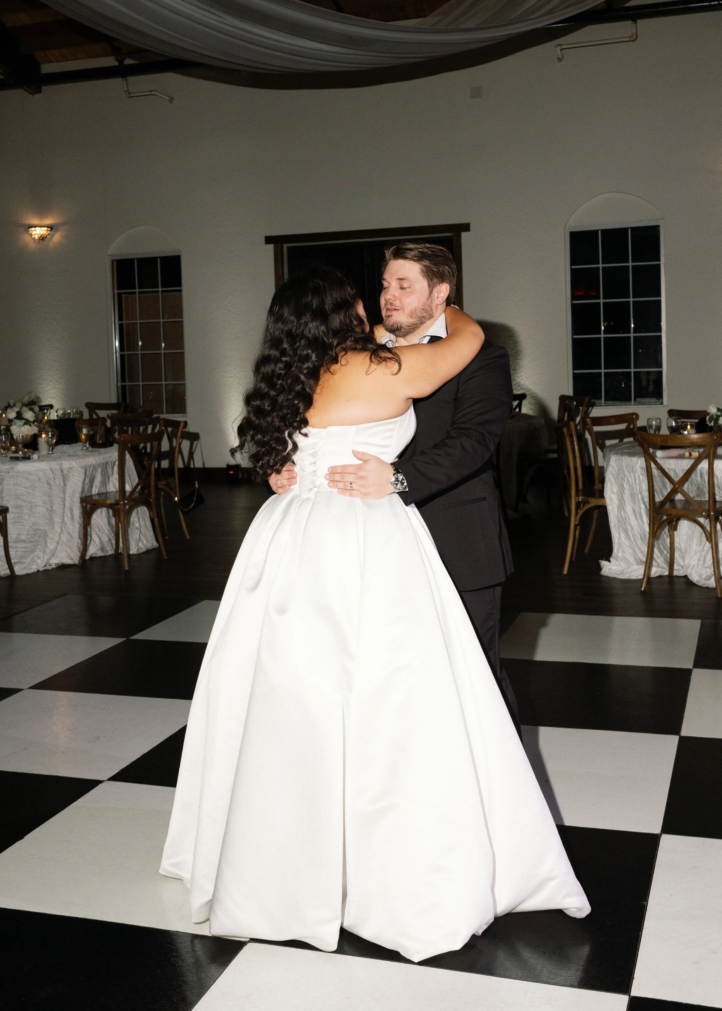 Bride and groom share their first dance on a black and white checkered dance floor at an Orlando Central Florida wedding reception venue