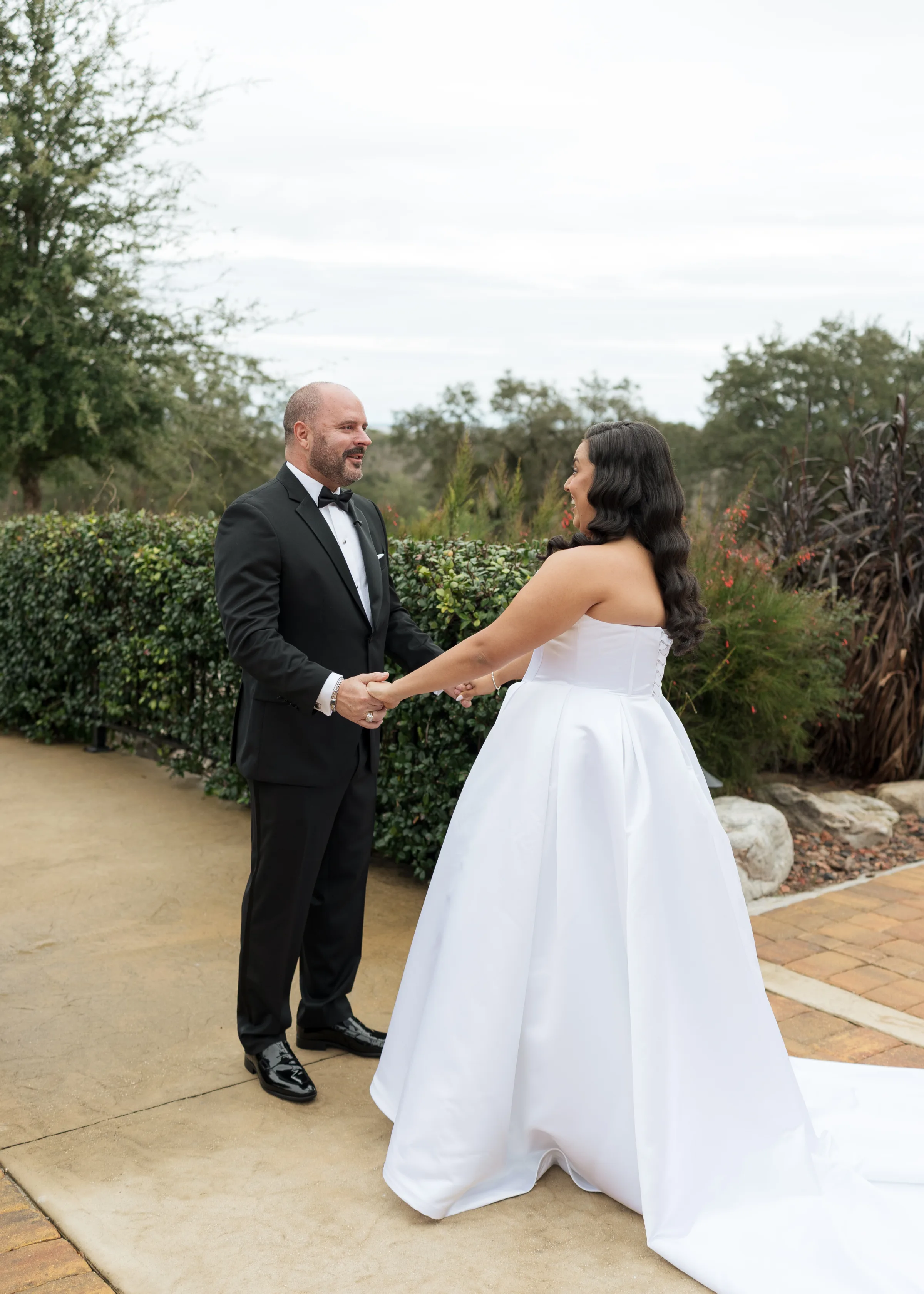Bride and groom share an emotional first look moment holding hands at an outdoor Central Florida wedding venue surrounded by lush greenery