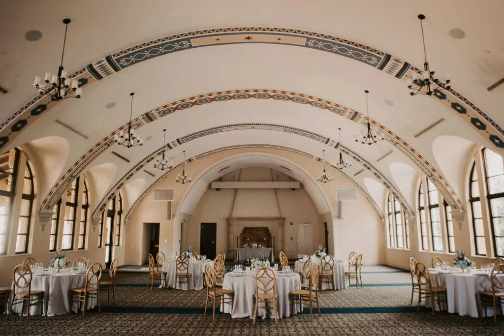 historic central florida wedding venue 1885 events at rollins college 1 - Wedding Venues Collections Elegant wedding reception hall with ornate painted barrel vault arches, gold Chiavari chairs, and white draped round tables set for a formal dinner at 1885 Events at Rollins College wedding venue in Central Florida