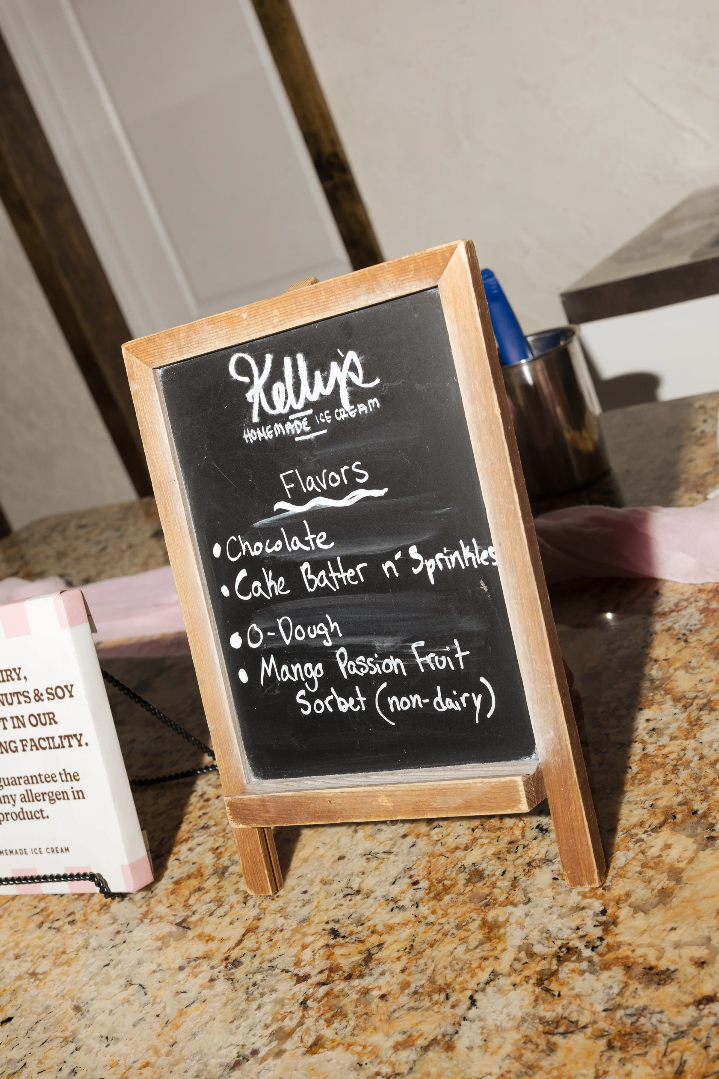 Kelly's Homemade Ice Cream chalkboard menu displaying chocolate, cake batter n sprinkles, O-dough, and mango passion fruit sorbet flavors at a Central Florida wedding reception