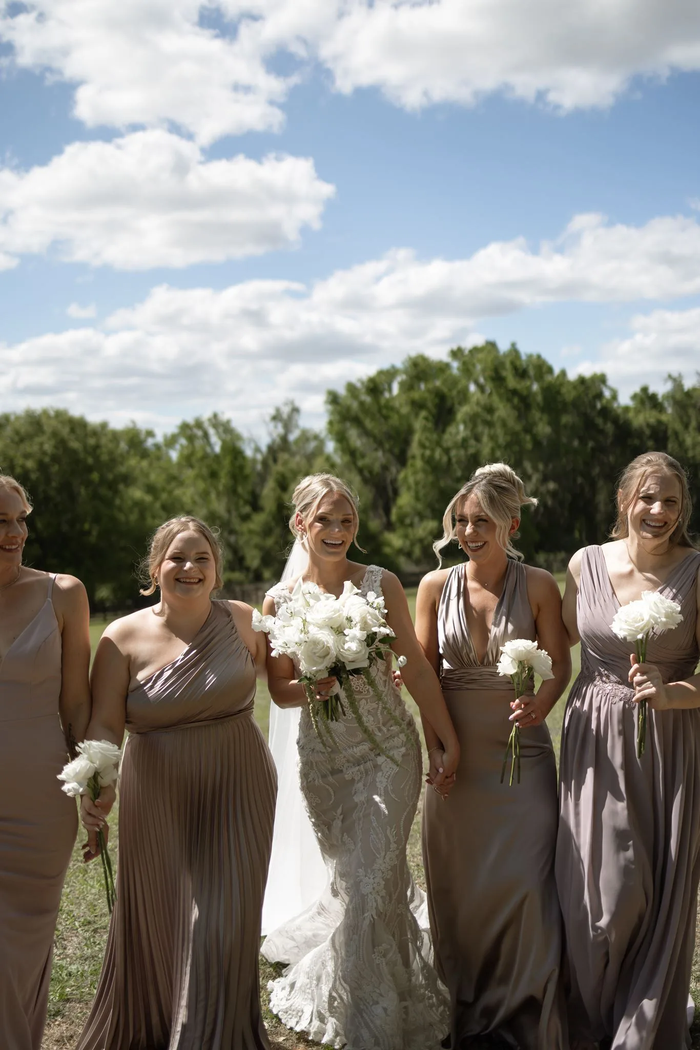 lilac ivory wedding bridesmaids la hacienda snow hill 2 - An Elegant Lilac and Ivory Wedding at La Hacienda on Snow Hill Bride in lace gown laughing with bridesmaids in taupe dresses holding white bouquets at La Hacienda on Snow Hill outdoor wedding in Central Florida