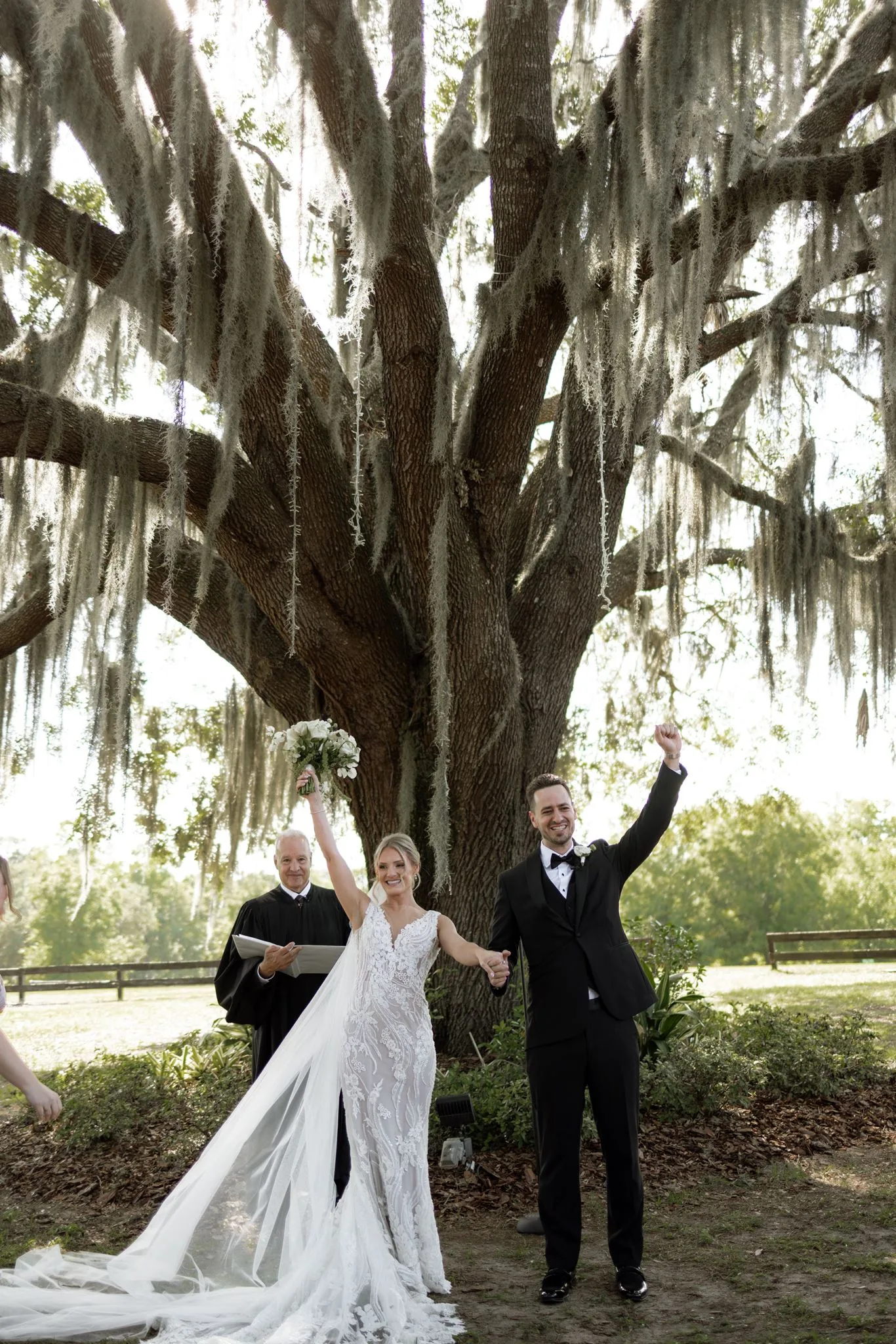 lilac ivory wedding ceremony la hacienda snow hill 1 - An Elegant Lilac and Ivory Wedding at La Hacienda on Snow Hill Bride and groom celebrate just-married moment raising hands under a grand live oak tree draped in Spanish moss at La Hacienda on Snow Hill in Central Florida