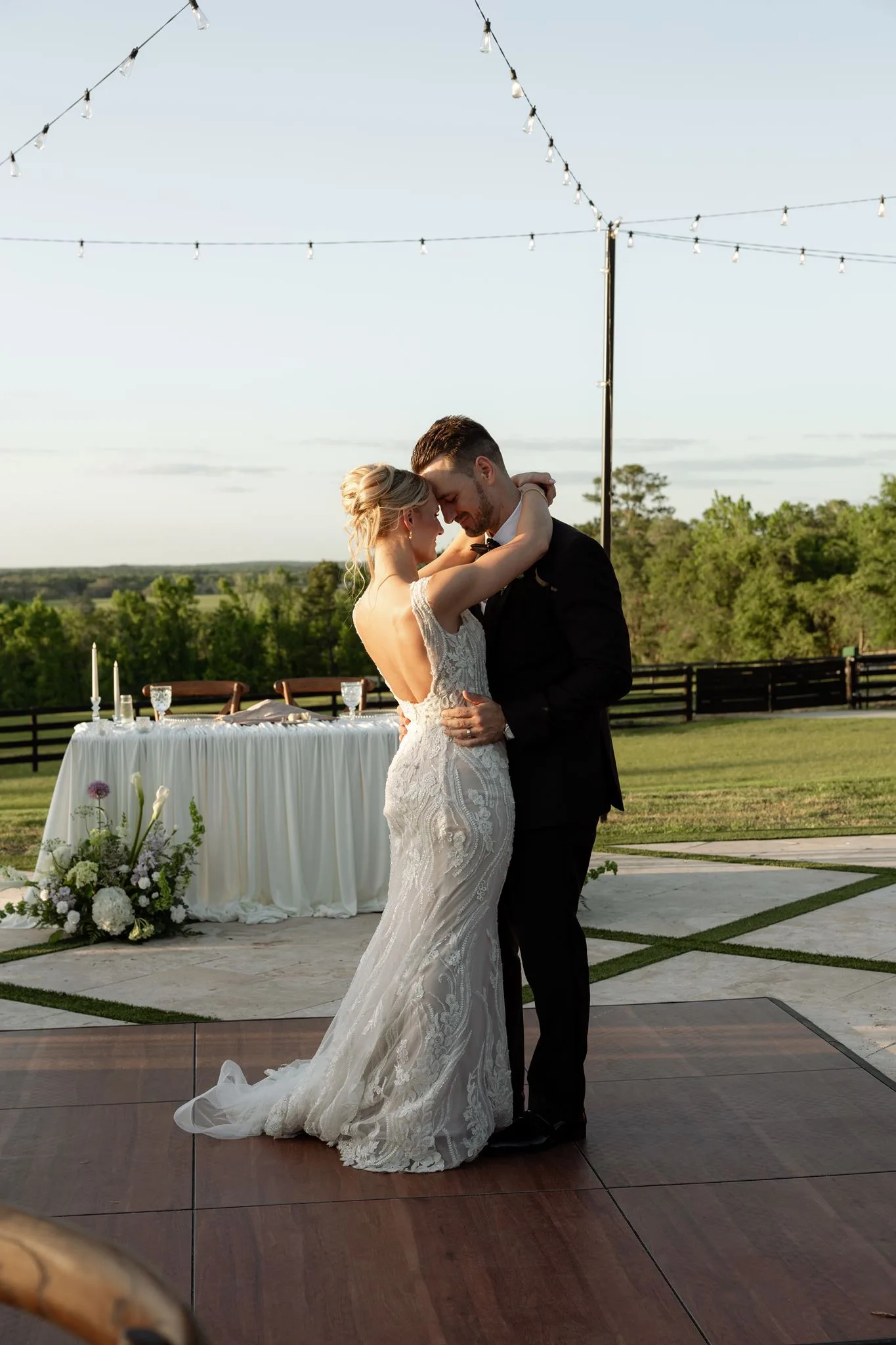 lilac ivory wedding first dance la hacienda snow hill 1 - An Elegant Lilac and Ivory Wedding at La Hacienda on Snow Hill Bride and groom share their first dance on an outdoor wooden dance floor at La Hacienda on Snow Hill, a Central Florida wedding venue, surrounded by string lights and lush greenery at golden hour