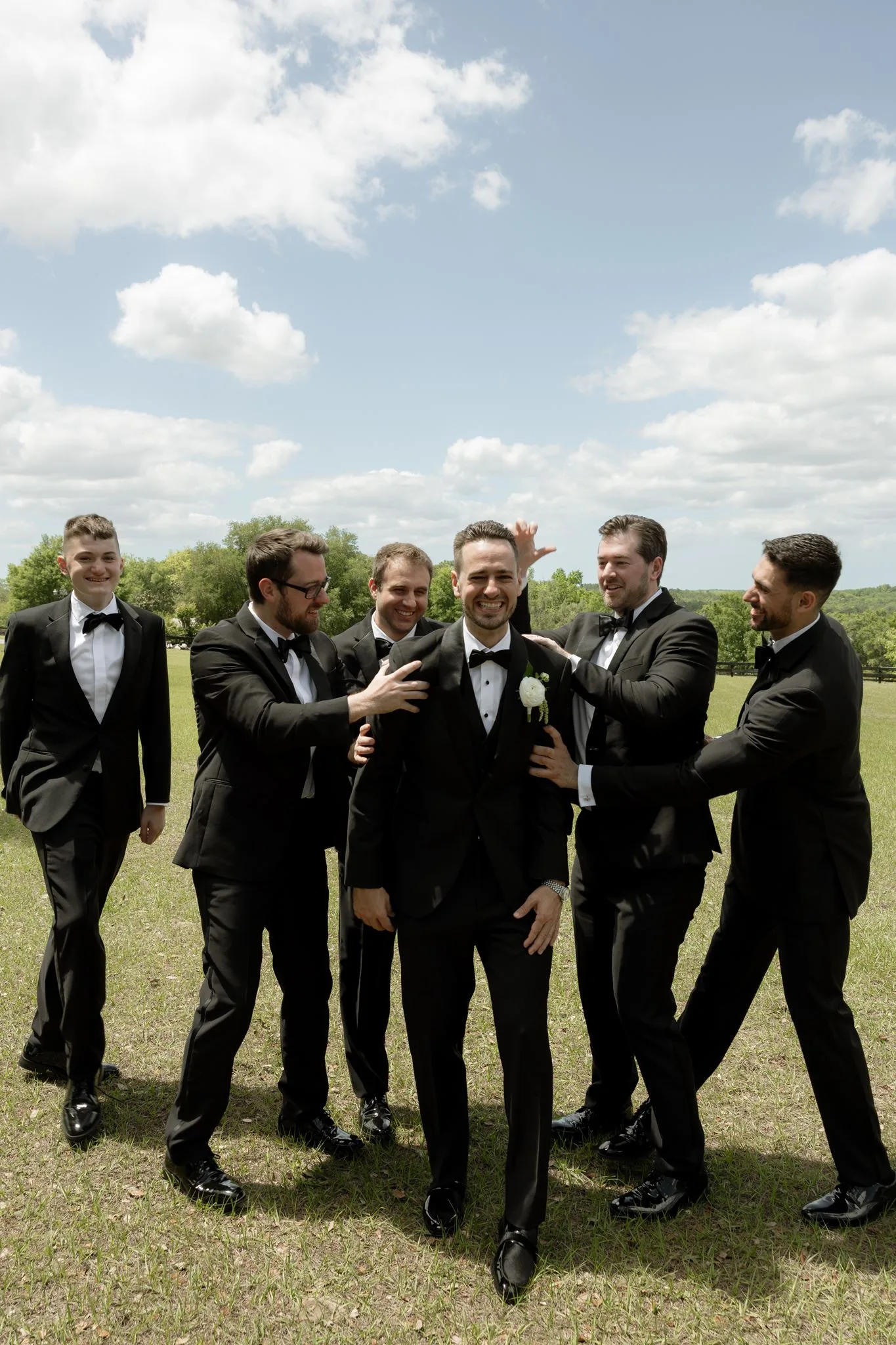 lilac ivory wedding groomsmen la hacienda snow hill - An Elegant Lilac and Ivory Wedding at La Hacienda on Snow Hill Groom and groomsmen laughing together in black tuxedos at La Hacienda on Snow Hill outdoor wedding venue in Central Florida