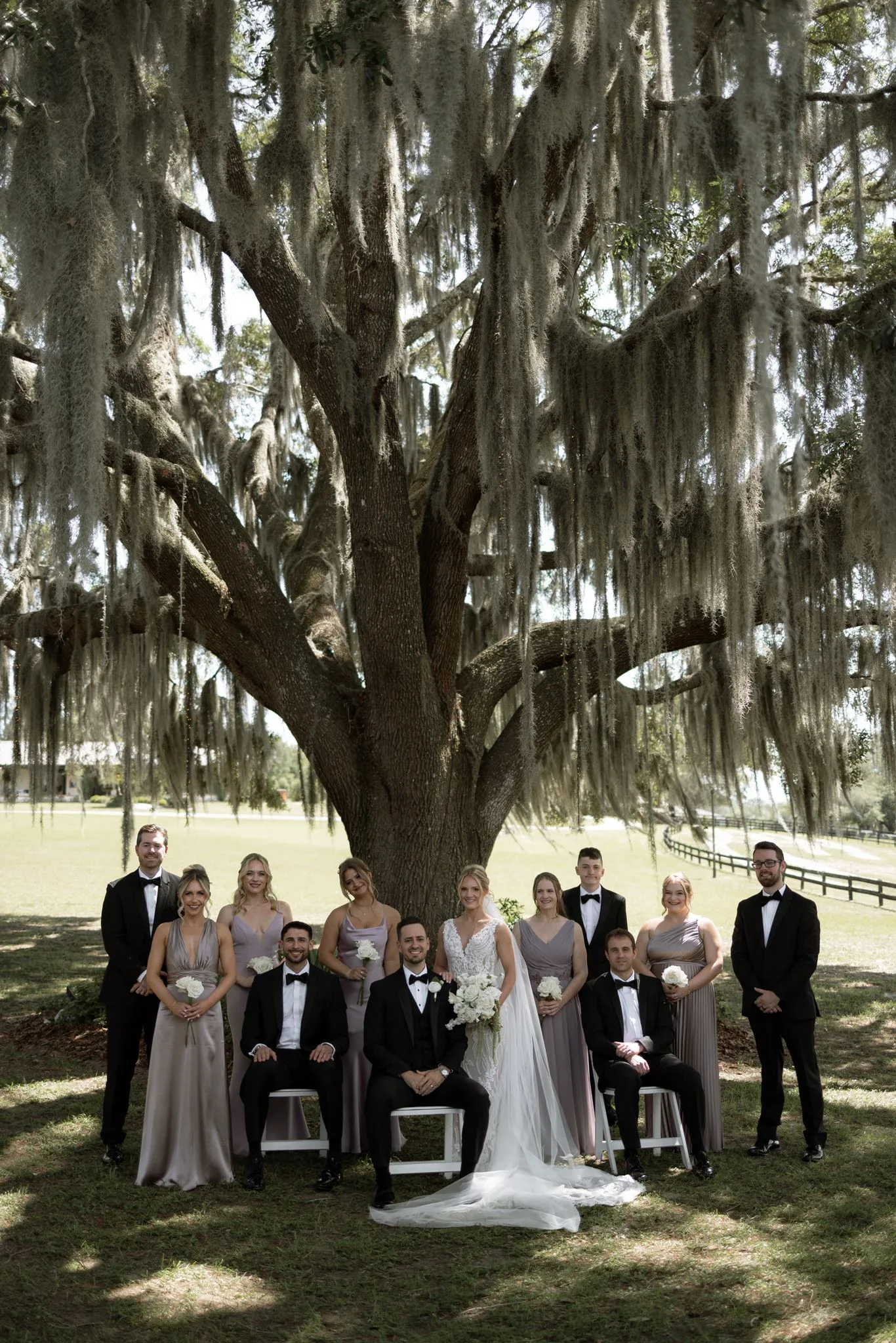 lilac ivory wedding party la hacienda snow hill - An Elegant Lilac and Ivory Wedding at La Hacienda on Snow Hill Wedding party in lilac bridesmaid gowns and black tuxedos posed under a sprawling Spanish moss oak tree at La Hacienda on Snow Hill in Central Florida for a lilac and ivory spring wedding