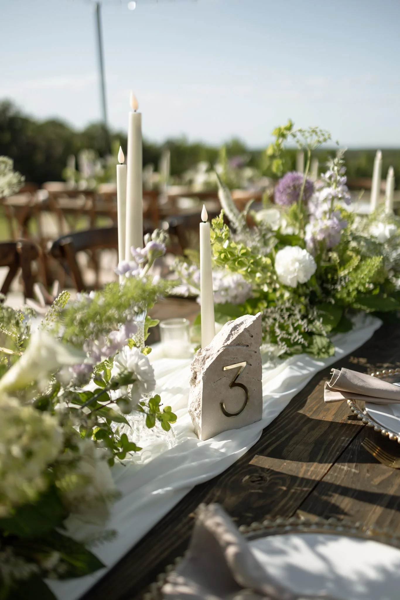 lilac ivory wedding tablescape florist la hacienda snow hill - An Elegant Lilac and Ivory Wedding at La Hacienda on Snow Hill Lilac and ivory wedding reception tablescape with tall taper candles, lush floral centerpieces, and a stone table number marker at La Hacienda on Snow Hill in Central Florida