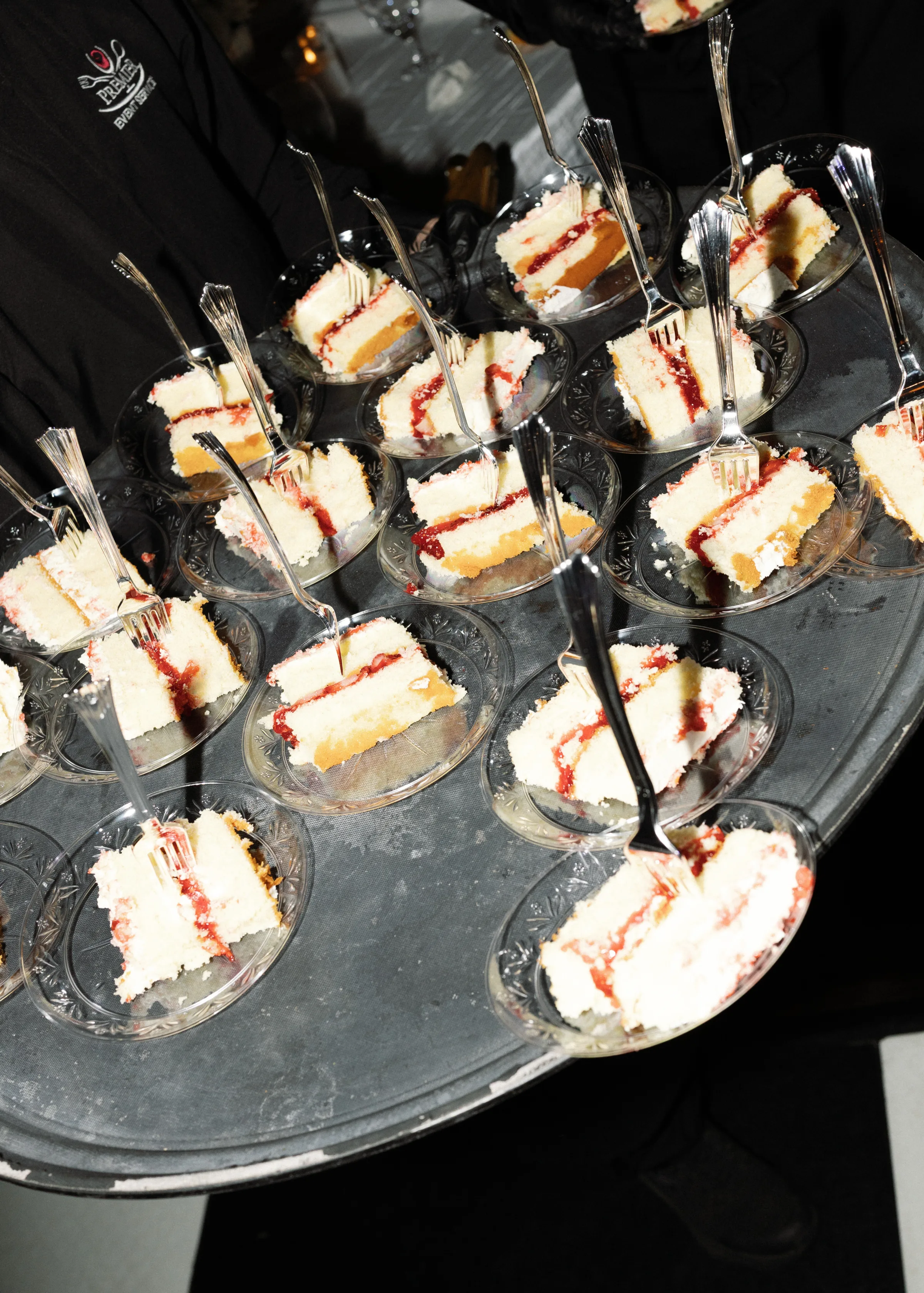 White layered wedding cake slices with raspberry filling served on individual glass plates on a silver tray by Premier Event Services catering staff in Orlando Florida