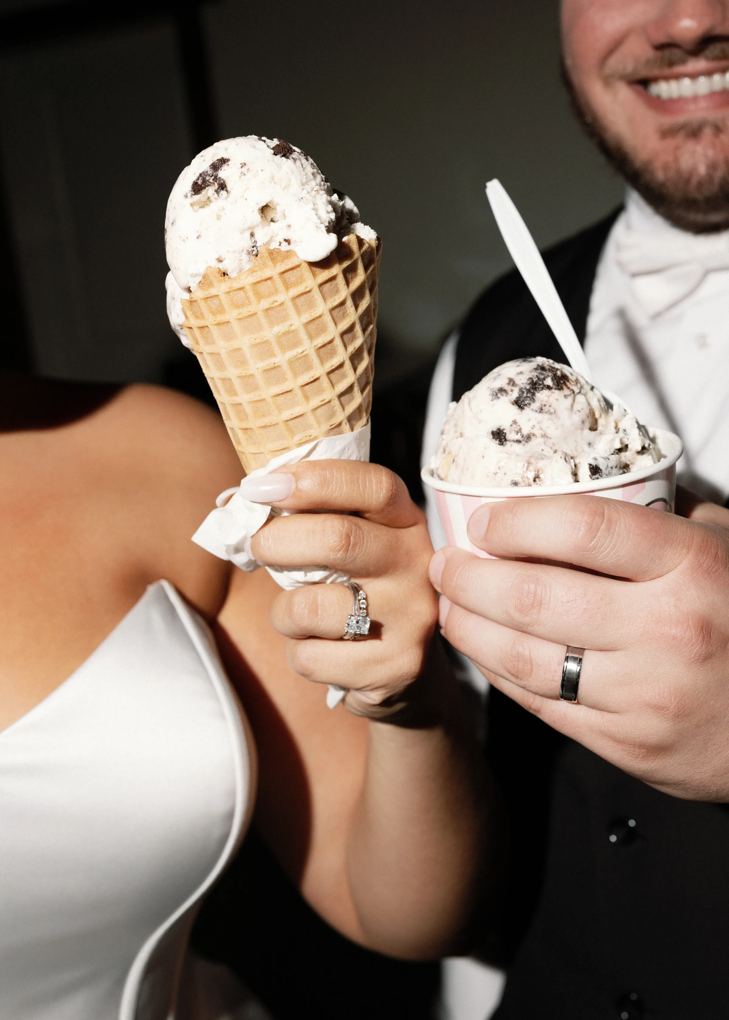 Newlywed bride and groom holding cookies and cream ice cream cone and cup at their Orlando wedding reception, showcasing a fun dessert alternative trend in Central Florida weddings