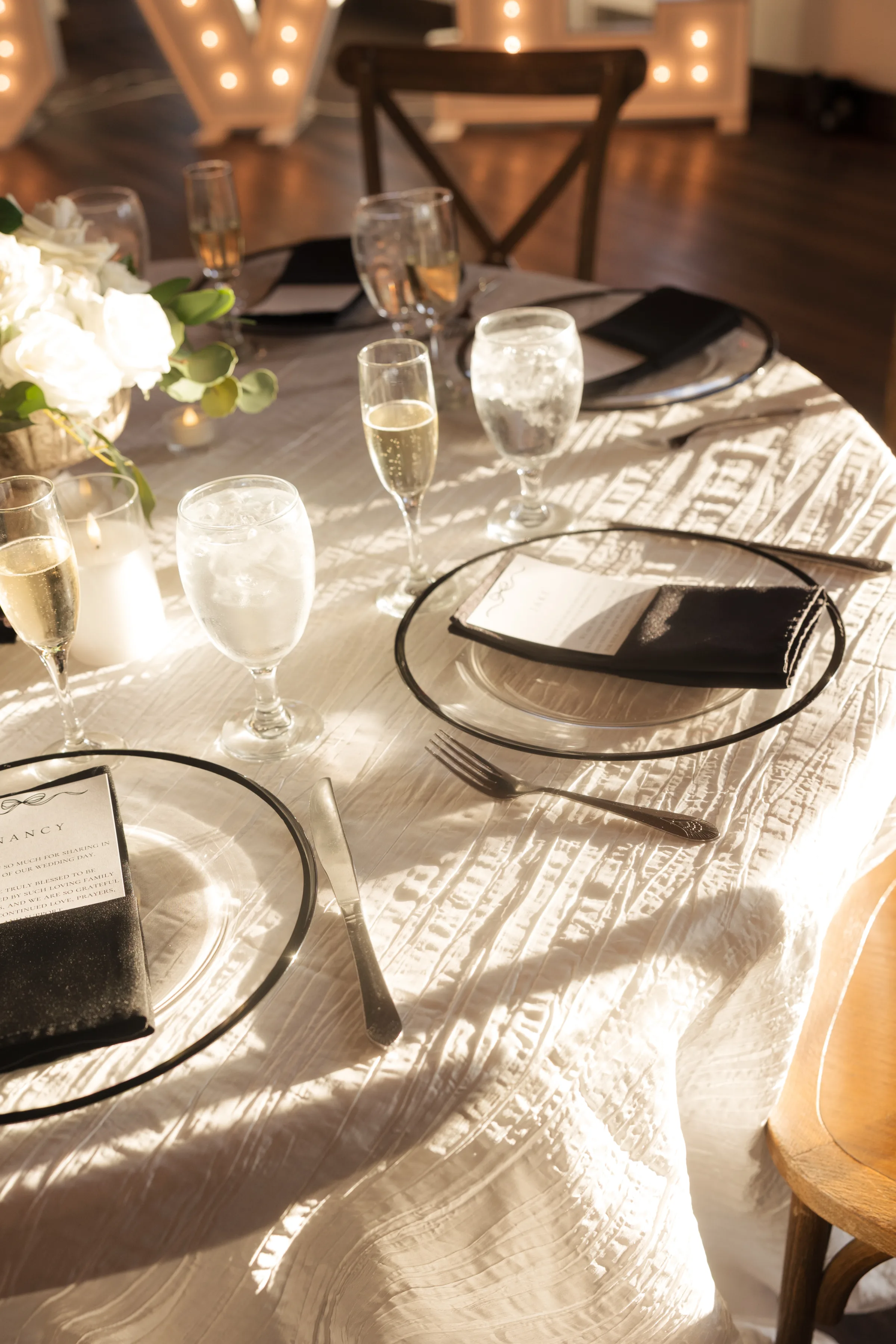 Elegant wedding reception tablescape with black-rimmed charger plates, black linen napkins, champagne flutes, and white floral centerpieces at an Orlando Central Florida wedding venue